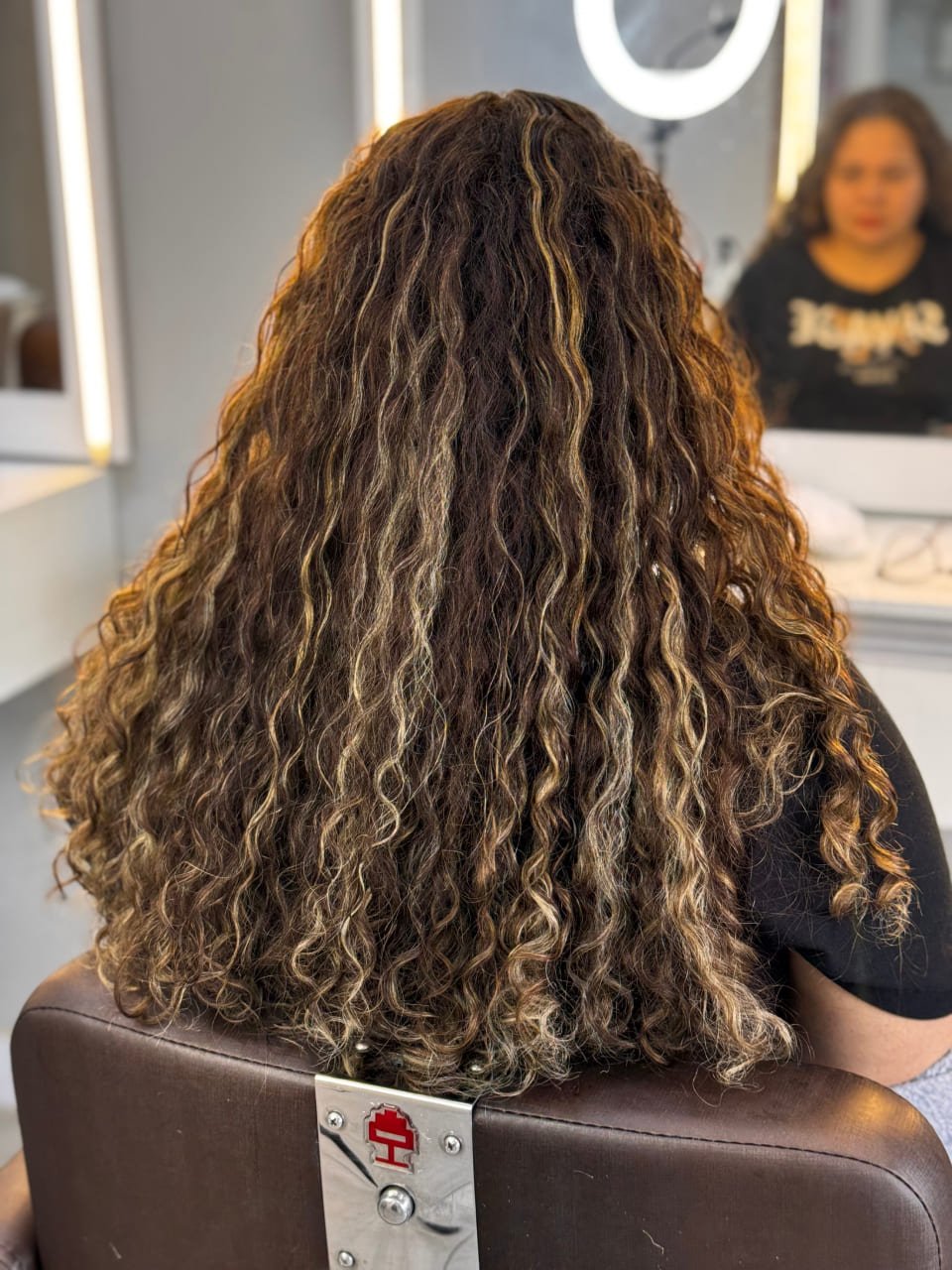 Cabelos cacheados com mechas iluminadas