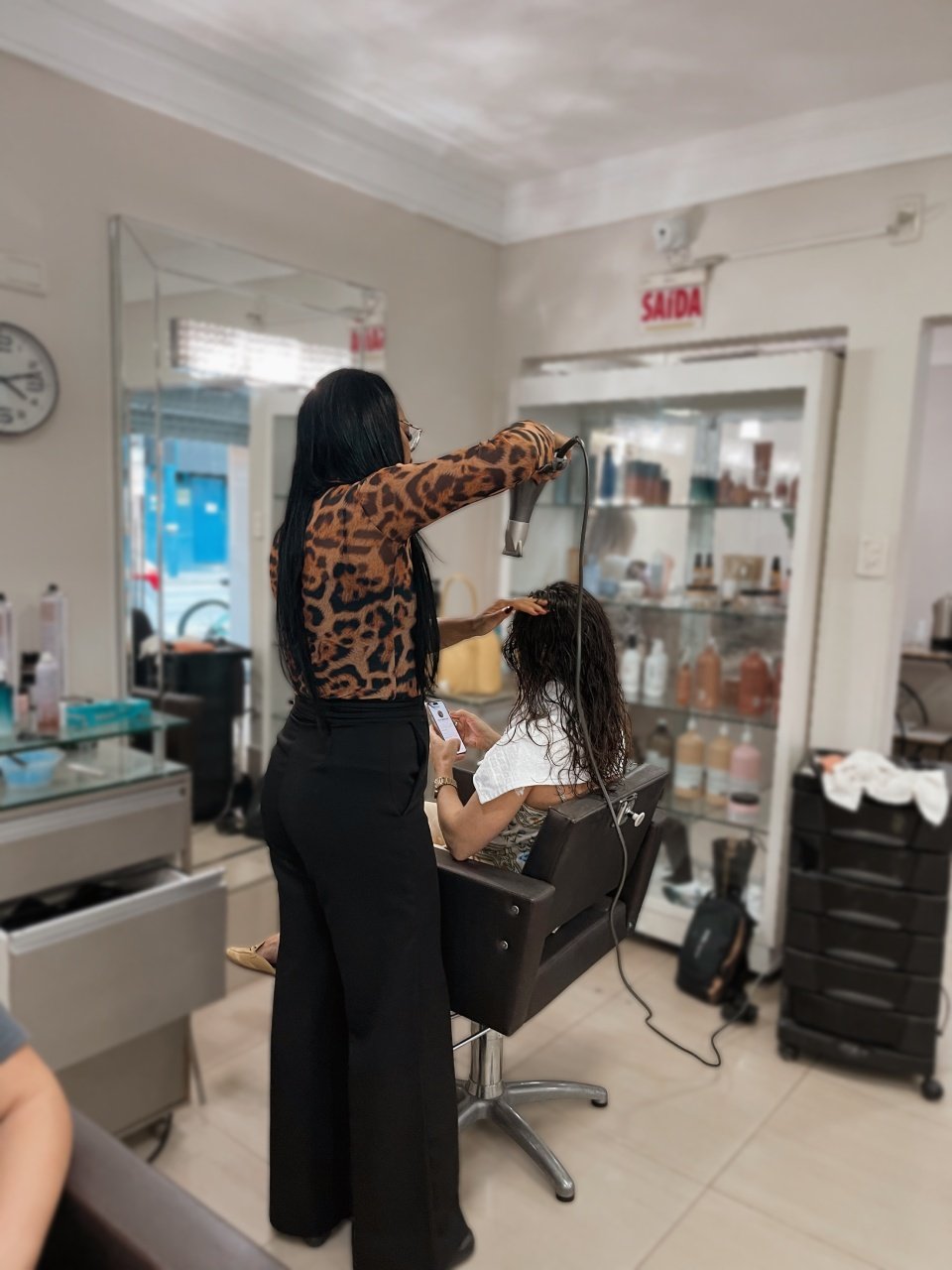 Claudia finalizando o cabelo de uma cliente no salão