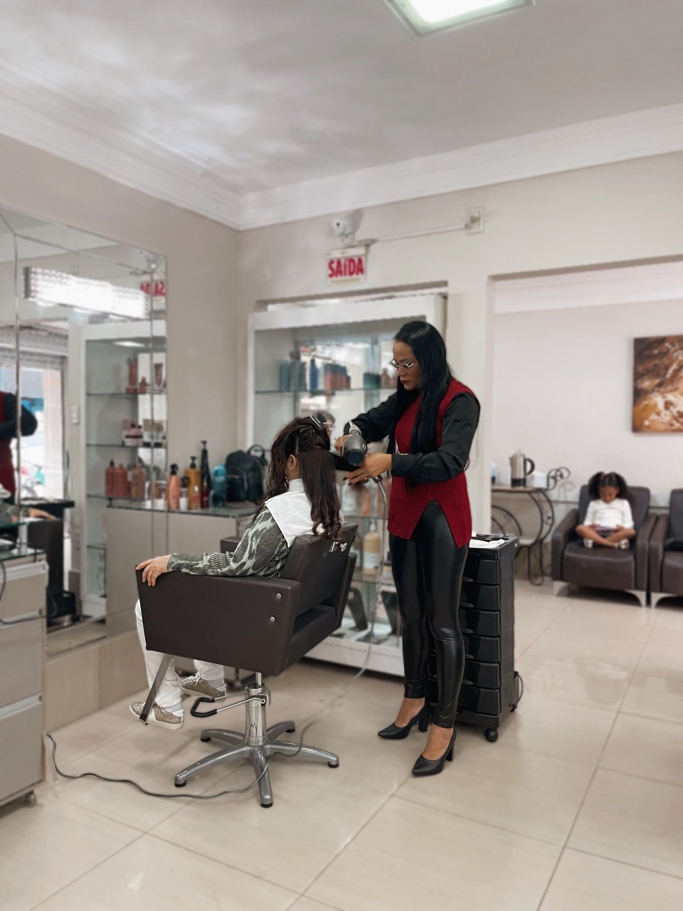 Claudia trabalhando no cabelo de uma cliente no salão
